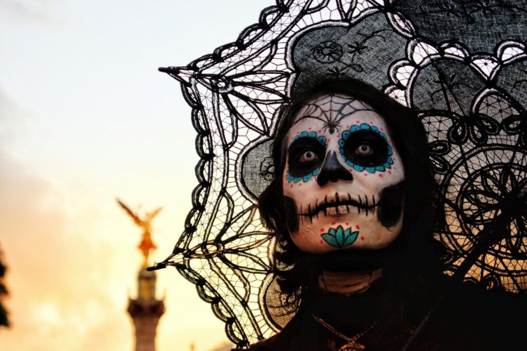 Une personne avec le visage peint et vêtue d'habits associés au Día de los Muertos