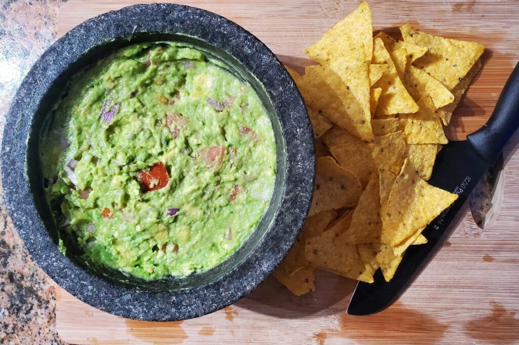 Un bol de guacamole, une sauce mexicaine traditionnelle, servie avec des chips tortilla.