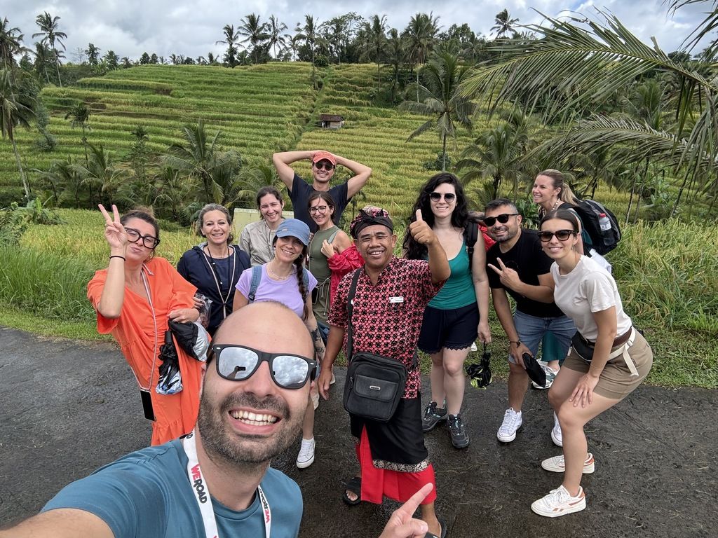 Groupe de voyageurs WeRoad posant devant des rizières en terrasses luxuriantes à Bali, lors d'un voyage organisé en Indonésie.