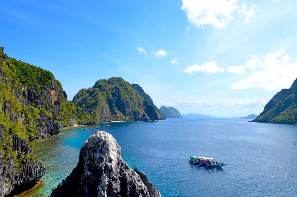 Paysage spectaculaire à El Nido, Philippines, avec des falaises rocheuses, une eau turquoise et un bateau traditionnel.