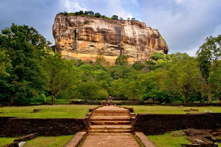 Vue du rocher du lion de Sigiriya, Sri Lanka, avec son escalier de briques au premier plan menant à la forteresse ancienne entourée de verdure luxuriante.