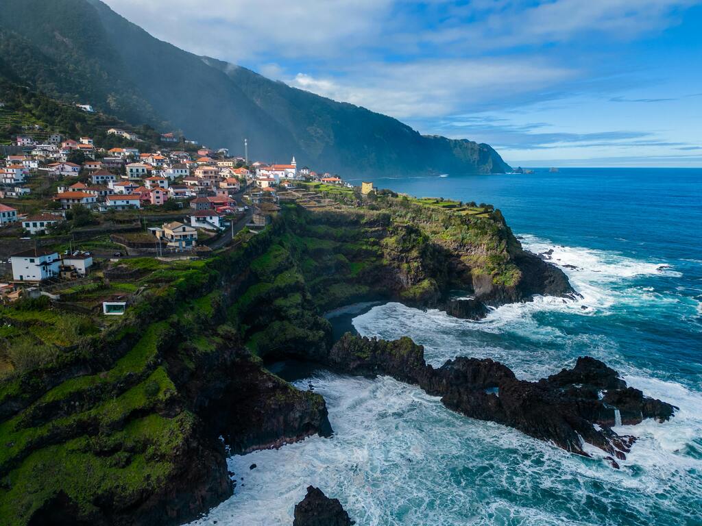 Paysage côtier à Madère avec falaises verdoyantes et mer agitée.