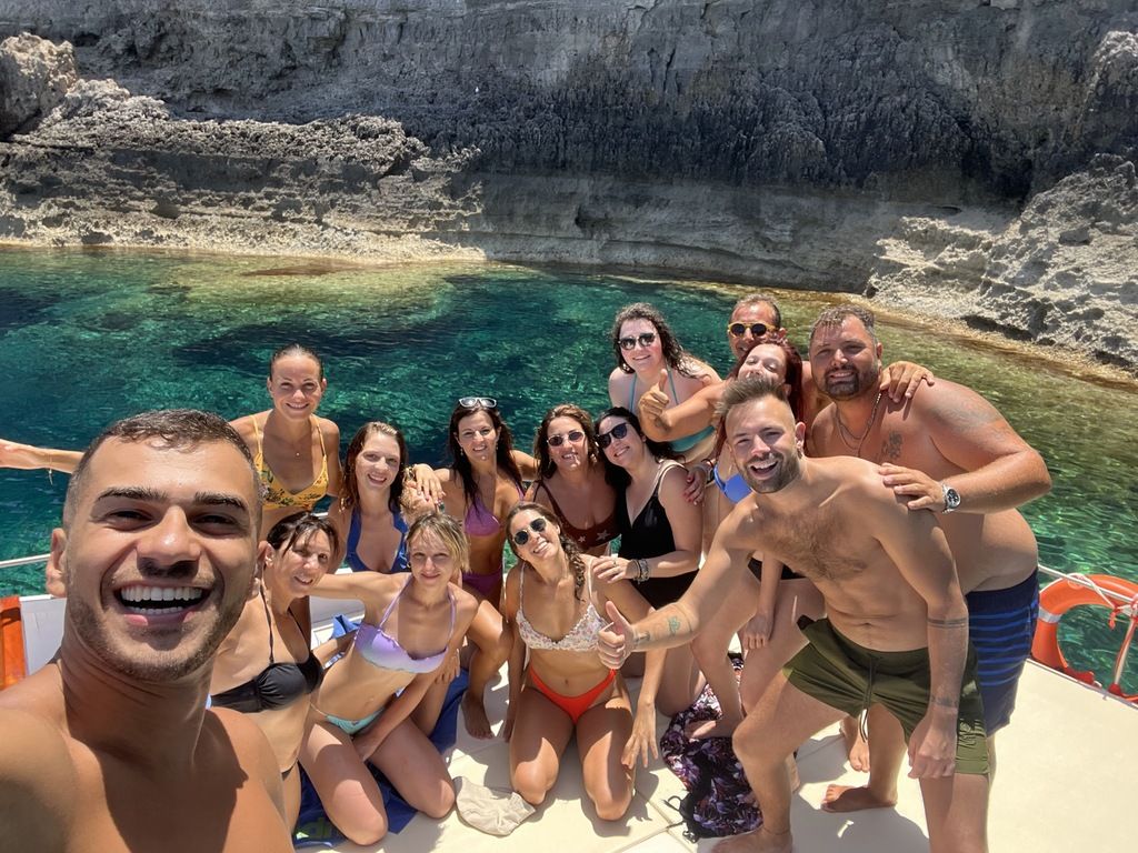 Un groupe de voyageurs WeRoad  profite d'une excursion en bateau dans une crique aux eaux cristallines.