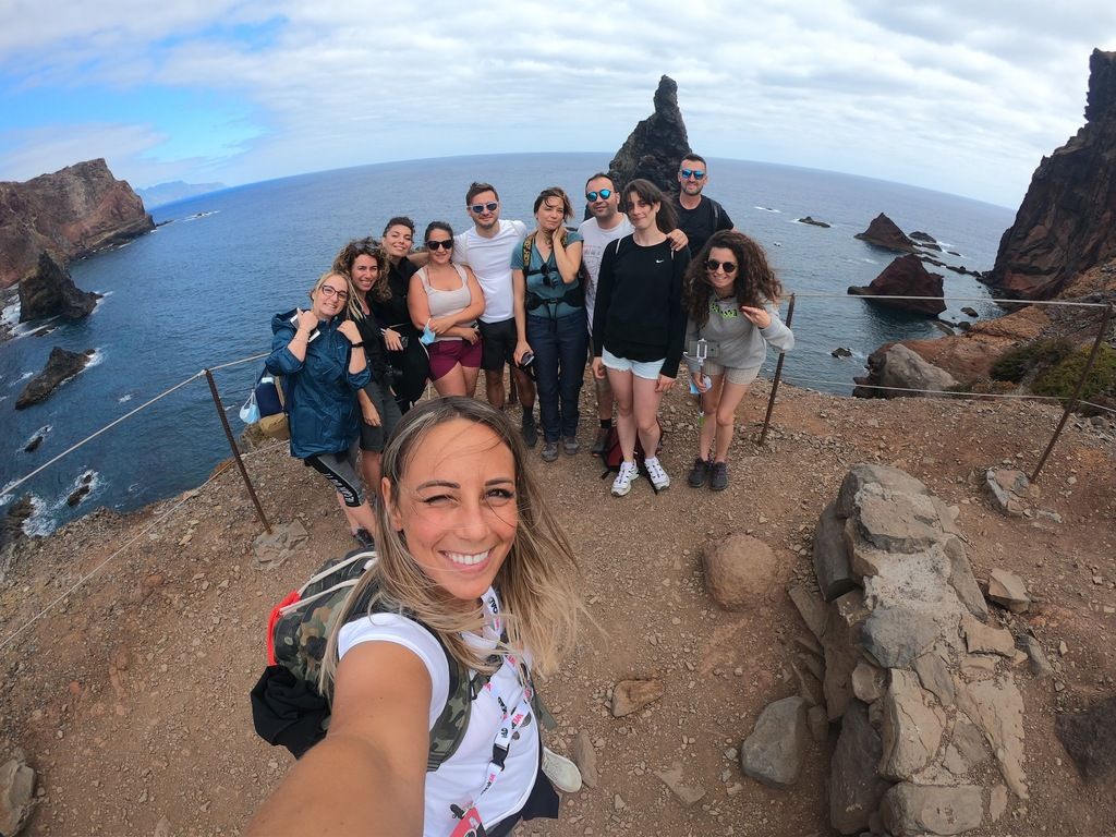 Groupe de voyageurs WeRoad explorant Madère avec vue sur la mer et formations rocheuses.