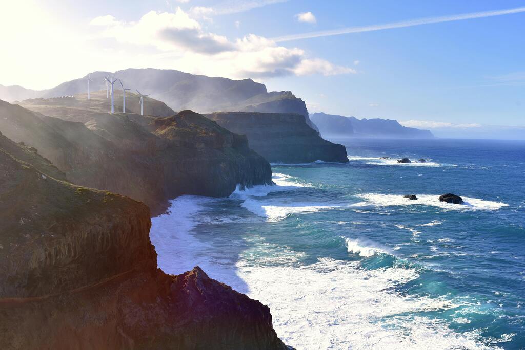Falaises spectaculaires au bord de l'océan avec éoliennes au sommet.
