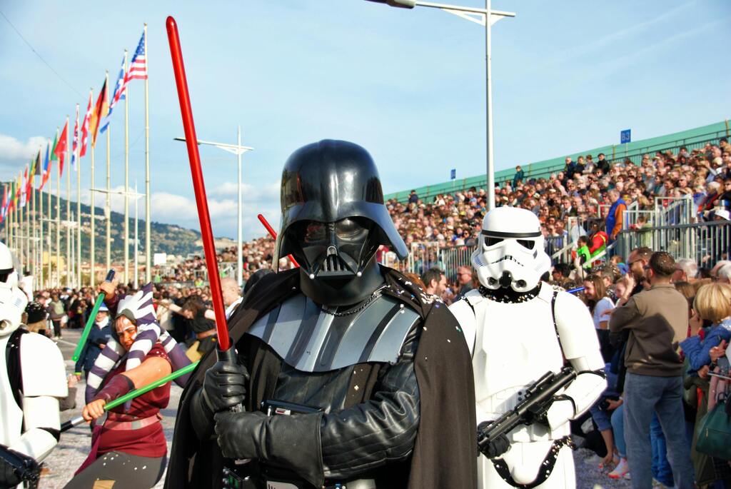 Personnages de Star Wars défilant avec Dark Vador et Stormtroopers devant une foule