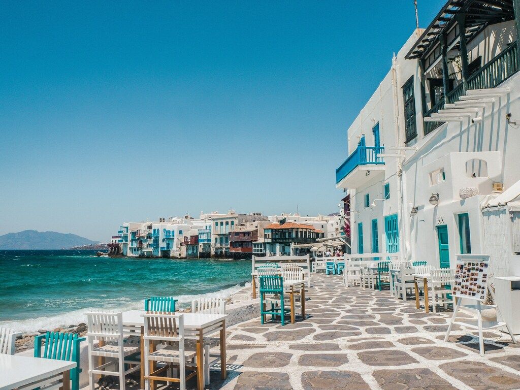 Terrasse en bord de mer à Mykonos avec bâtiments blancs et volets bleus