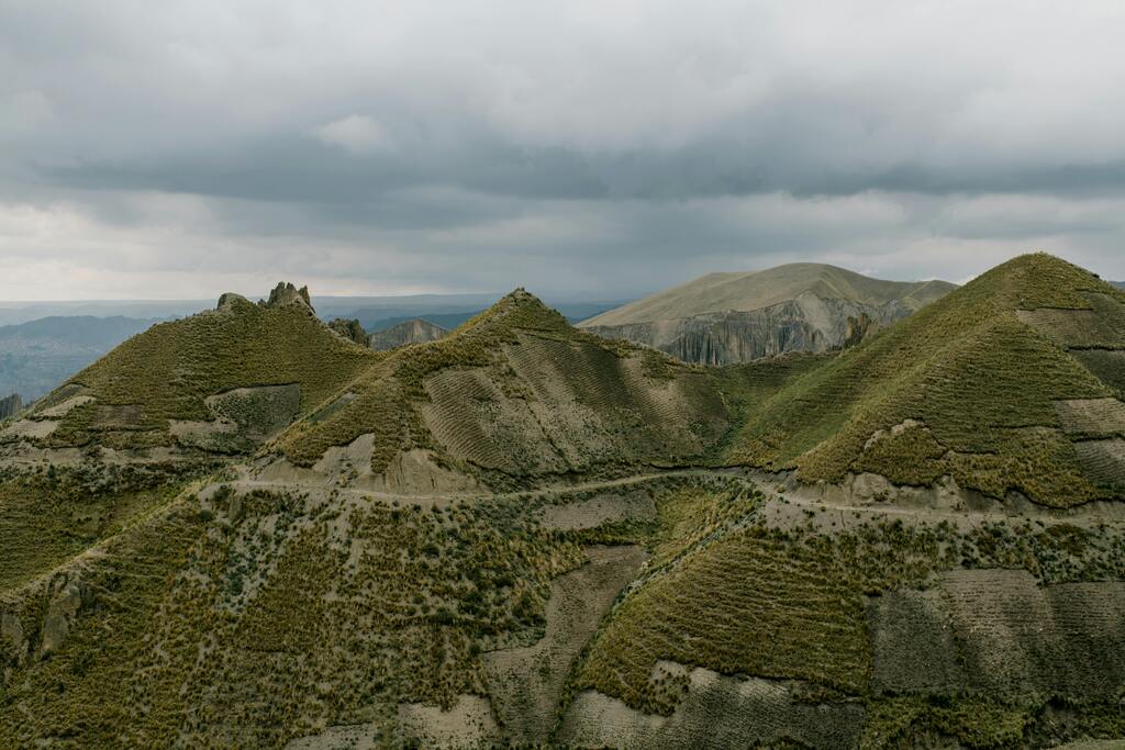 Collines verdoyantes et terres agricoles sous un ciel orageux en Bolivie