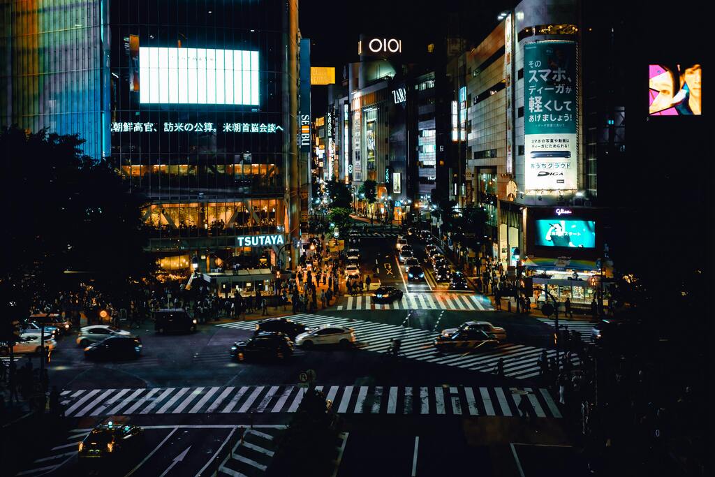 Vue nocturne du célèbre carrefour de Shibuya, bondé de passants et de voitures.
