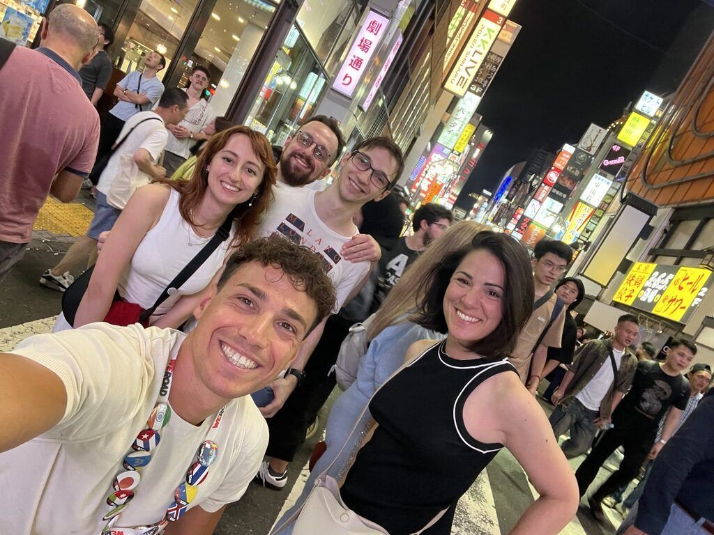 Groupe de voyageurs WeRoad posant joyeusement dans une rue animée de Tokyo.
