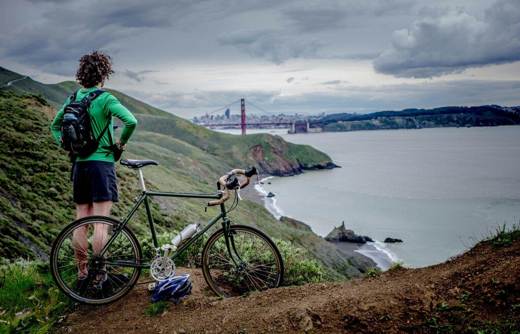 Cycliste admirant la vue sur le Golden Gate Bridge depuis un sentier côtier en Californie.