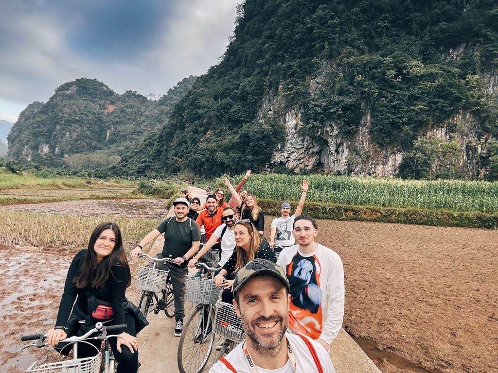 Groupe de voyageurs WeRoad faisant du vélo à travers les rizières et les montagnes du Vietnam.