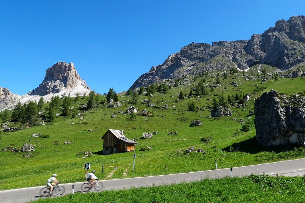 Cyclistes traversant une route de montagne dans les Dolomites, symbole de l’aventure à vélo en pleine nature.