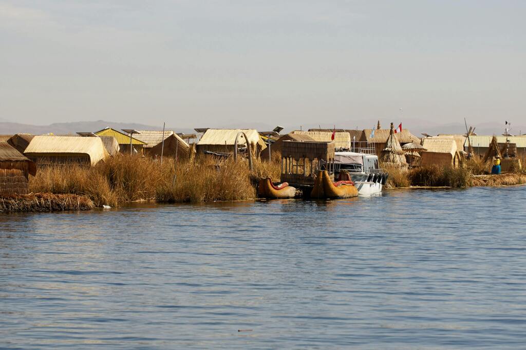 Maisons traditionnelles en roseau des îles flottantes sur le lac Titicaca, avec des barques typiques.