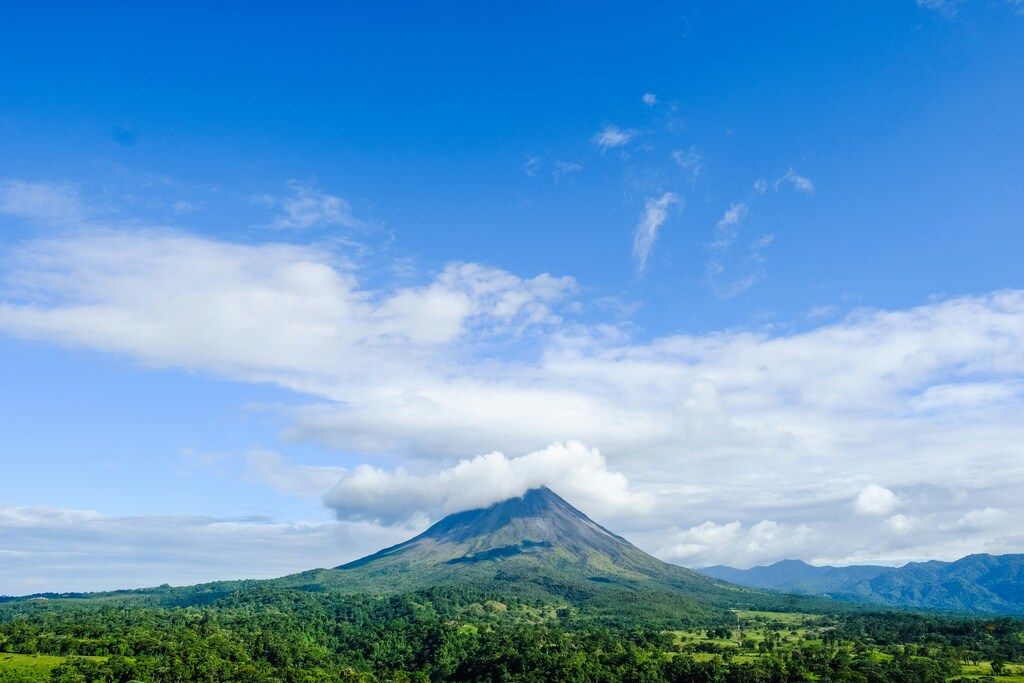 Volcan Arenal en arrière-plan avec forêt tropicale et ciel bleu nuageux