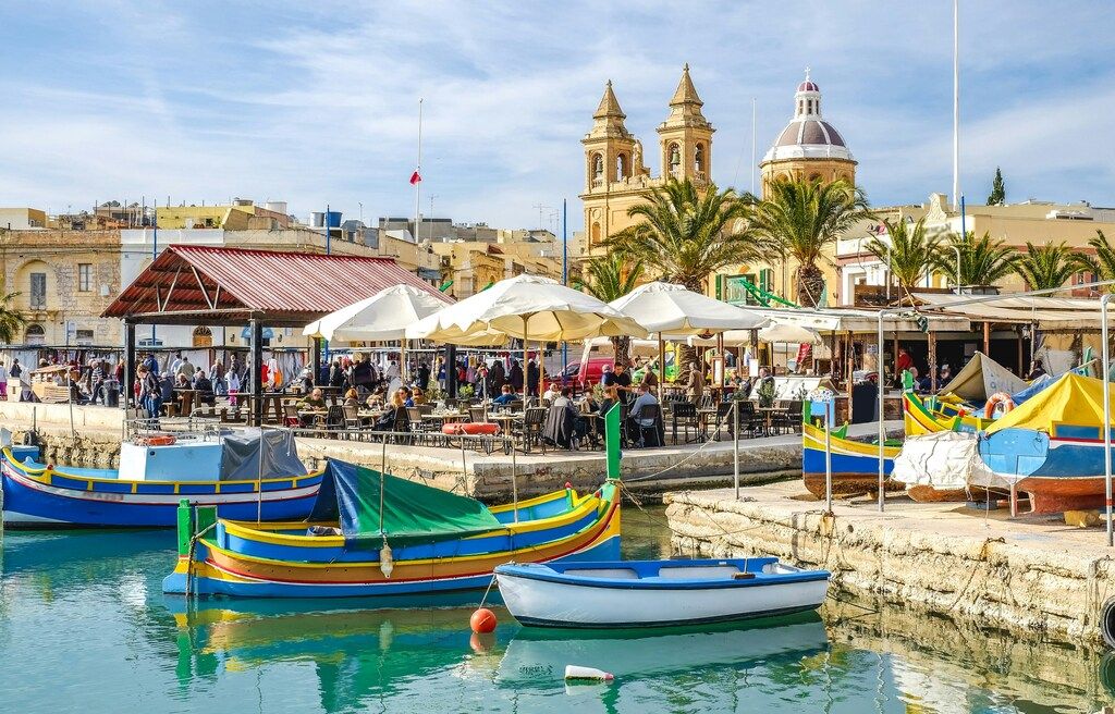 Vue du port de Marsaxlokk avec ses bateaux colorés et son marché animé, Malte