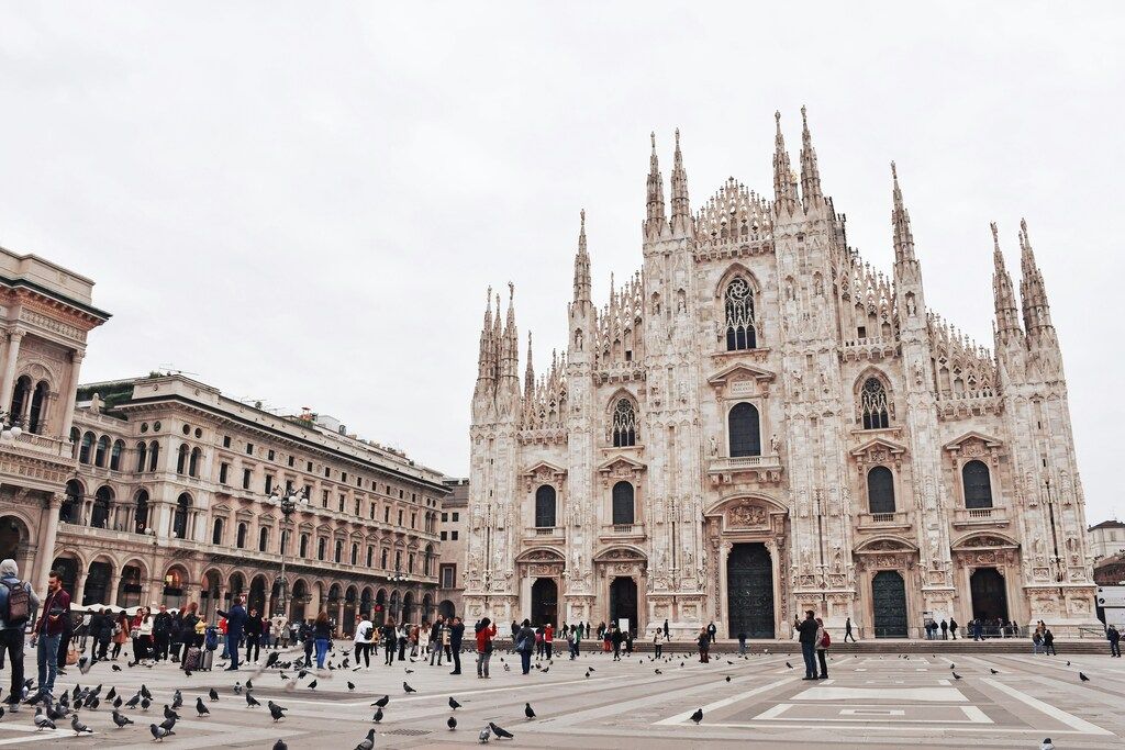 Façade gothique spectaculaire du Duomo de Milan avec des touristes sur la place centrale.