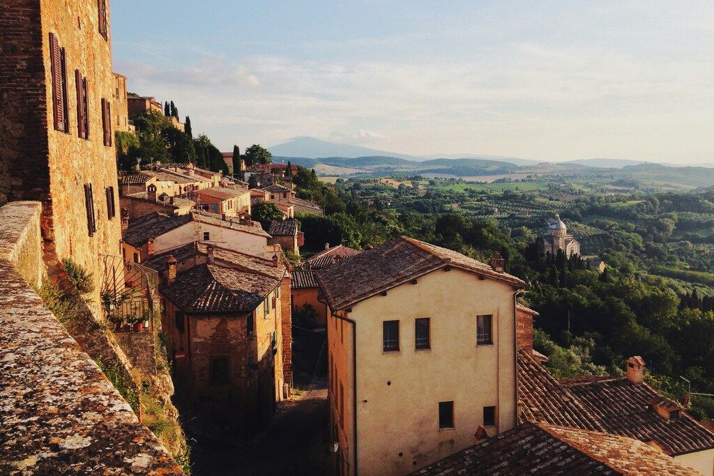 Charmant village médiéval en Toscane avec des toits en tuiles et vue sur la campagne vallonnée.