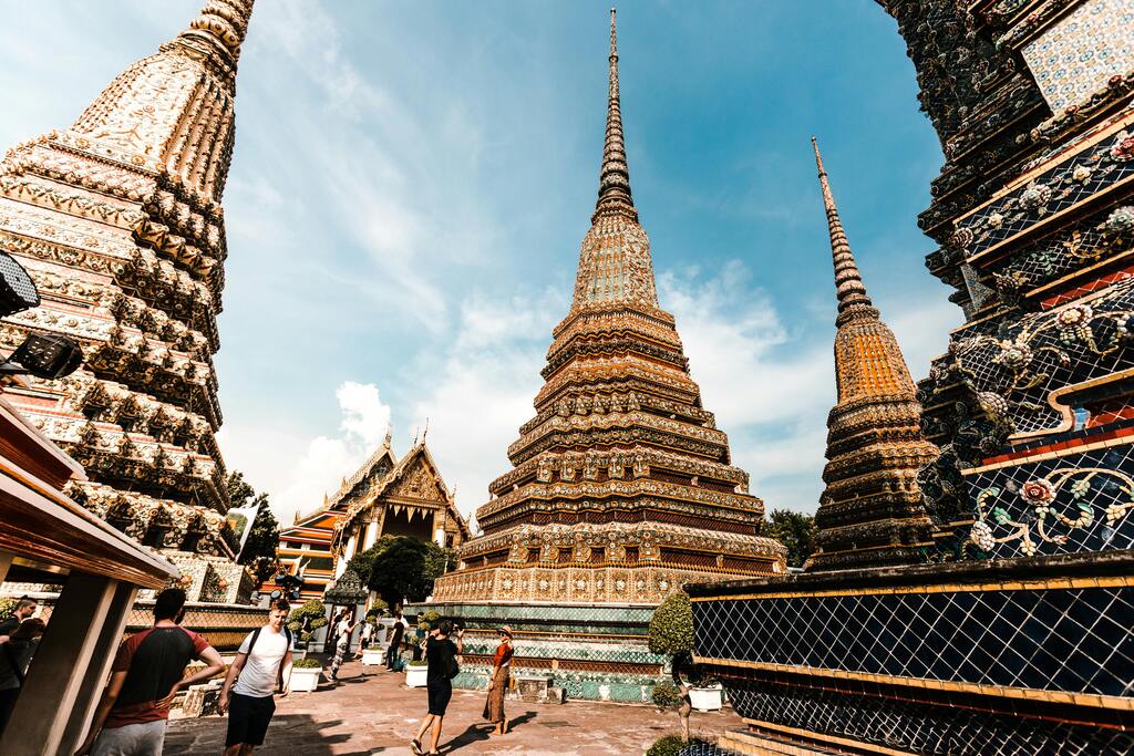 Tours ornées (chedis) et temples bouddhistes du Wat Pho sous un ciel bleu.