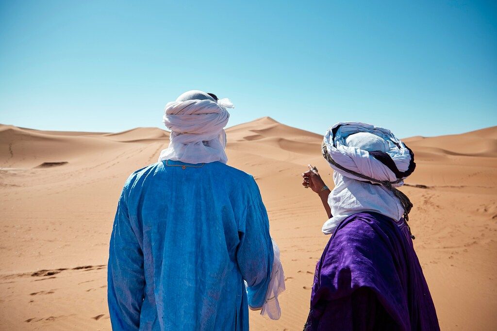 Deux hommes en habits traditionnels regardant l'horizon désertique du Sahara
