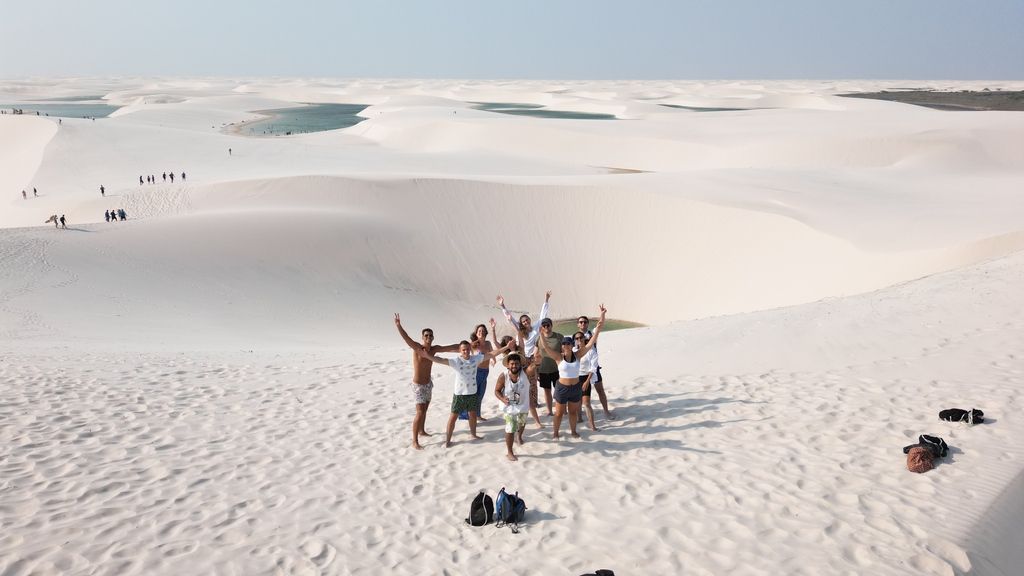 Voyageurs WeRoad posant avec enthousiasme sur les dunes de sable blanc du parc national des Lençóis Maranhenses au Brésil.