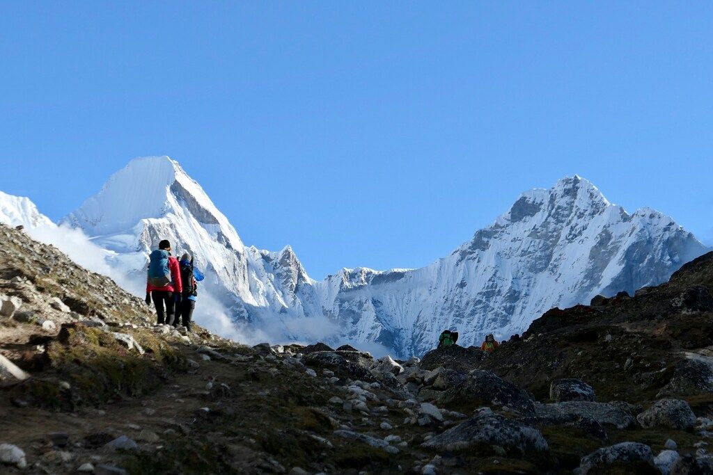 Randonneurs en chemin vers les sommets, entourés de paysages rocheux et enneigés.