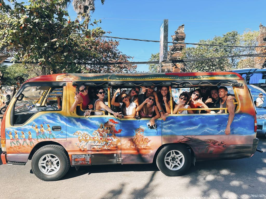 Groupe de voyageurs WeRoad souriants à bord d’un minibus décoré à Bali, lors d’un voyage en Indonésie.