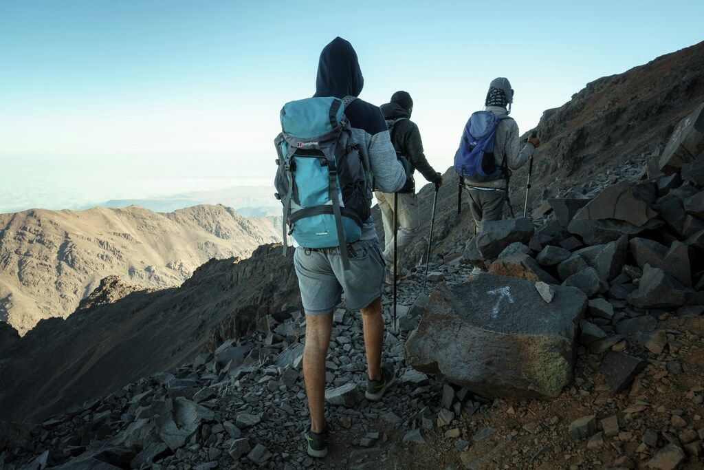 Groupe de randonneurs gravissant un sentier rocheux dans les montagnes de l'Atlas