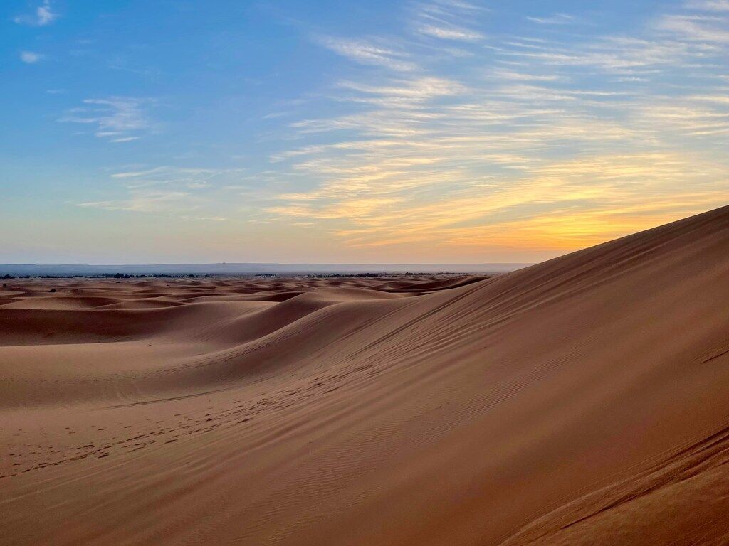 Dunes dorées du Sahara au coucher du soleil sous un ciel pastel