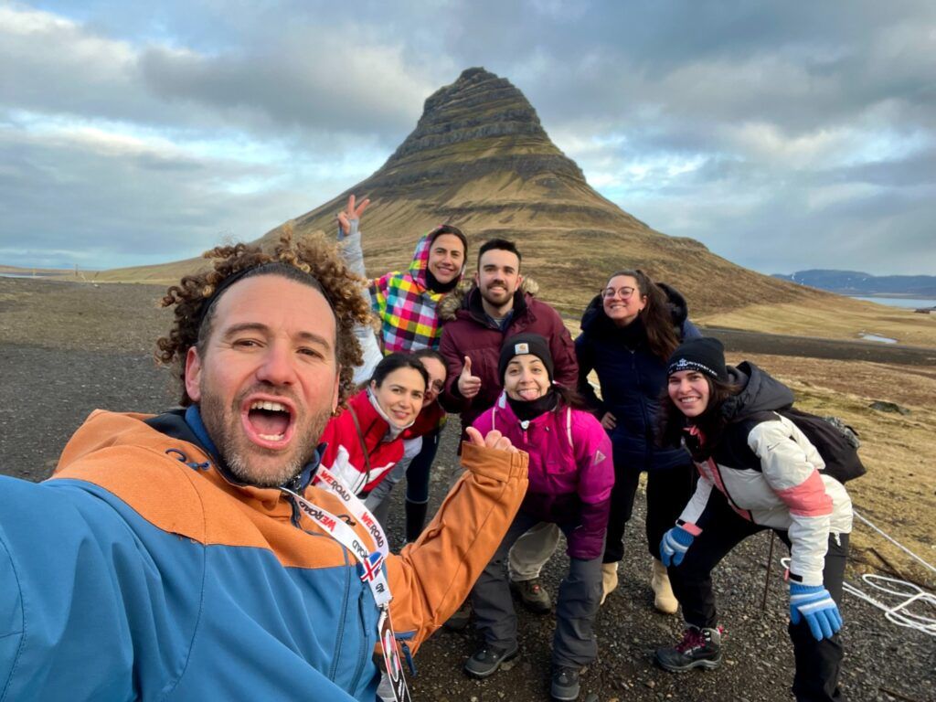 Des voyageurs Weroad posent pour un selfie de groupe au pied de la montagne de Kirkjufell en Islande.
