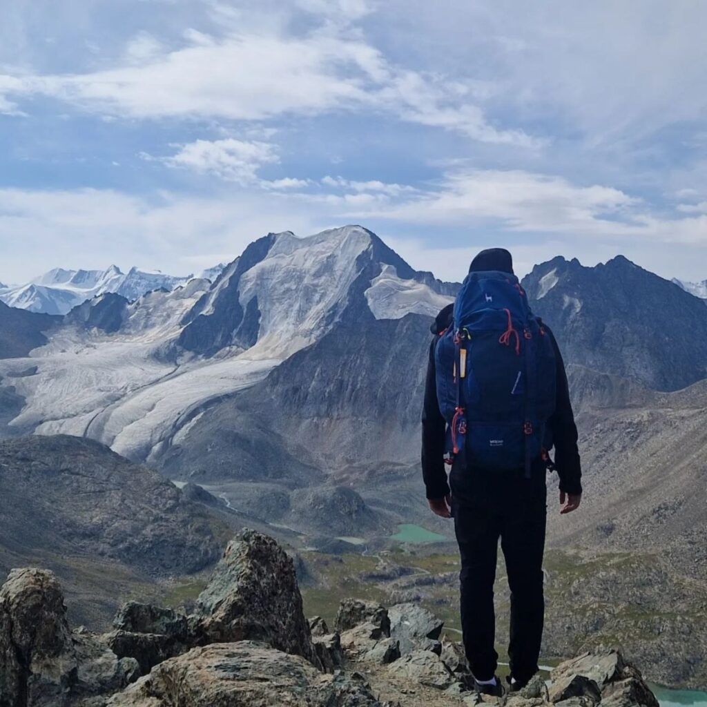 Randonneur de dos contemplant le paysage montagneux du Kirghizistan.