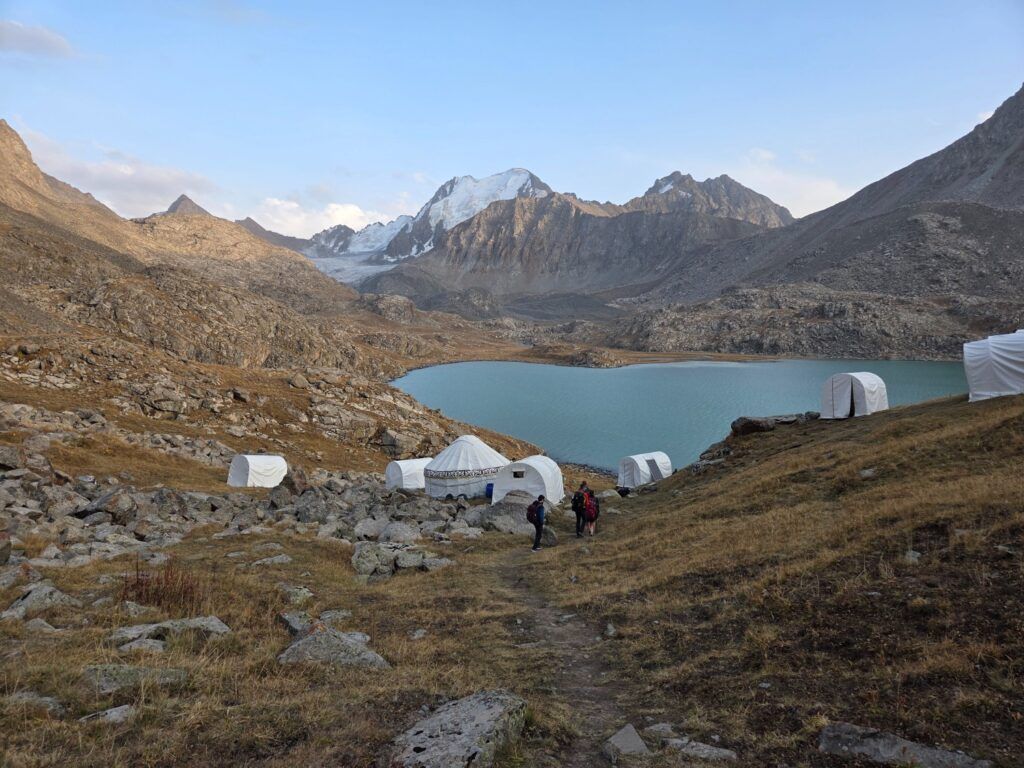 Un campement de yourtes et de tentes près du lac Ala-Kul, entouré de montagnes au Kirghizistan.