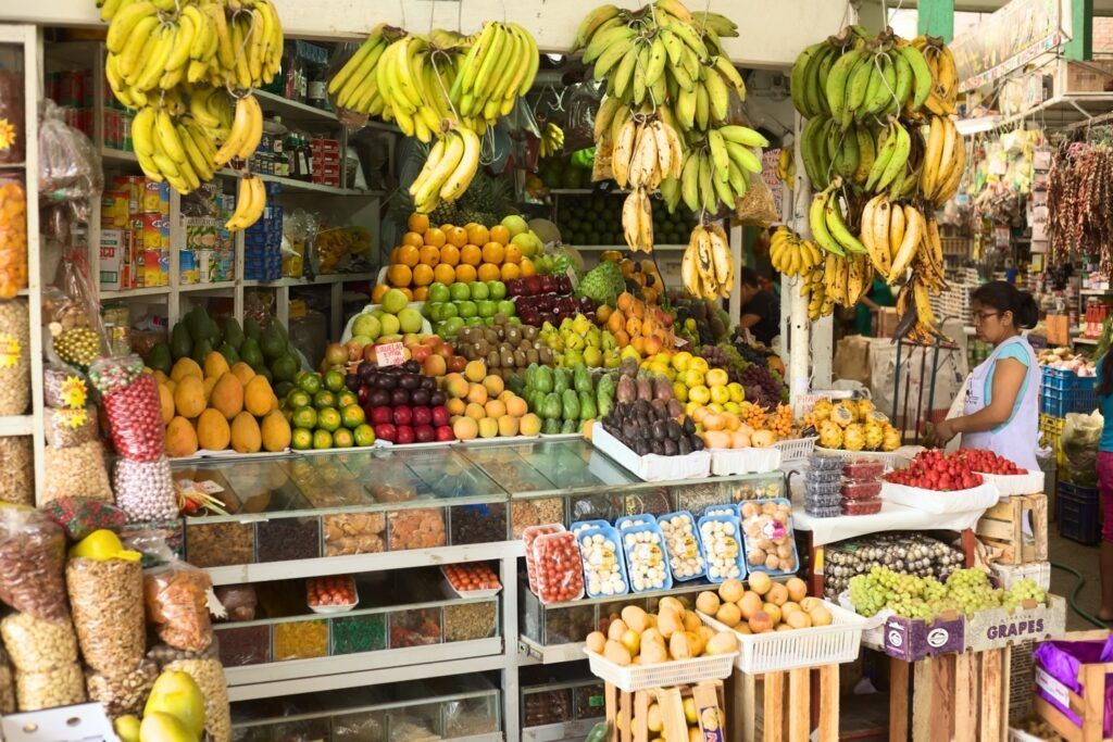 Marché regorgeant de fruits frais variés tels que bananes, mangues et raisins.