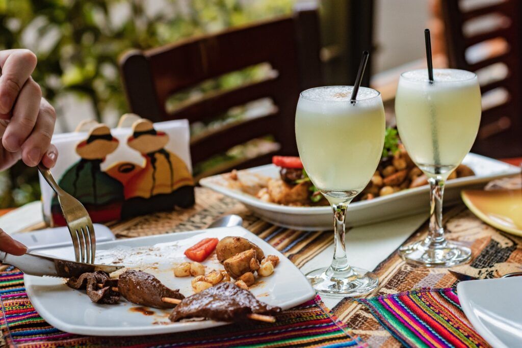 Cocktail Pisco Sour et Anticuchos (brochettes de cœur de bœuf) sur une terrasse péruvienne.