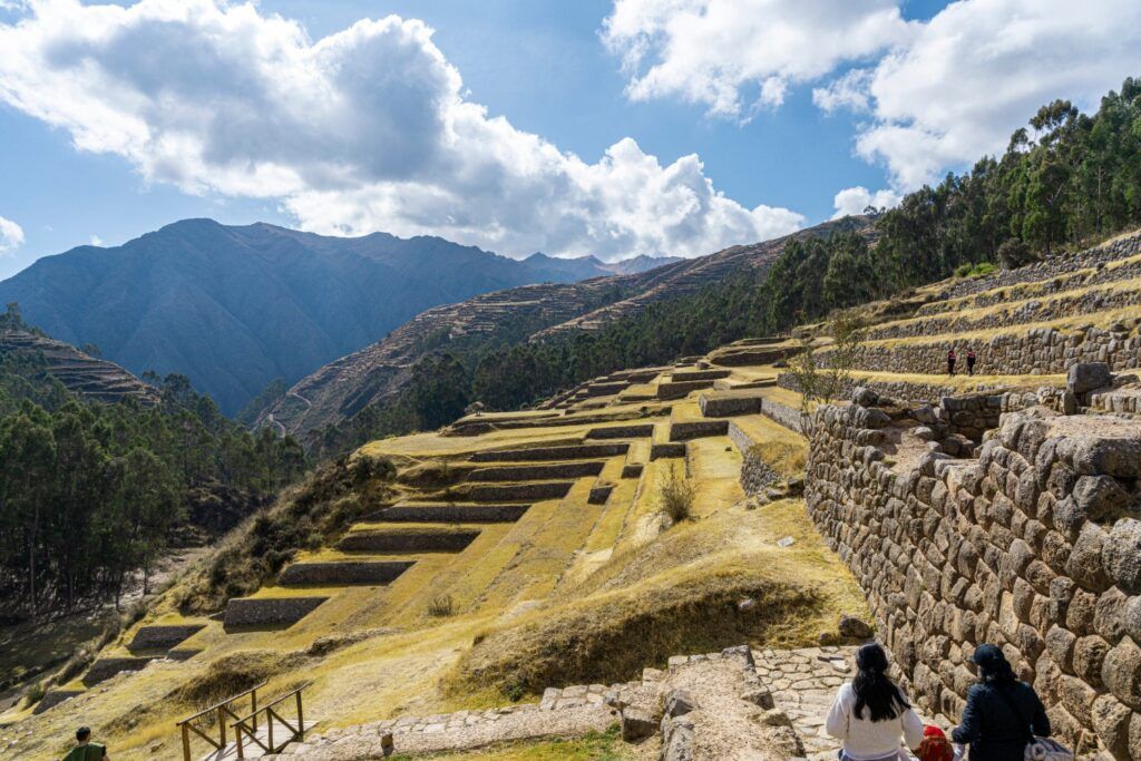 Ruines incas montrant de vastes terrasses agricoles en pierre qui s'étirent le long d'une pente de montagne.
