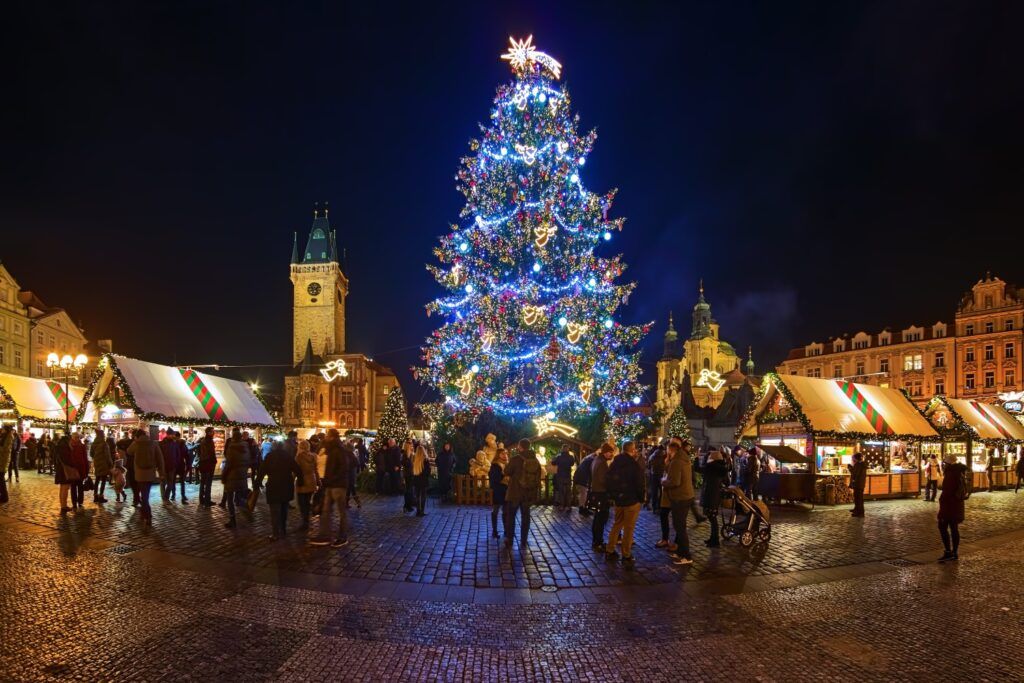 Immense sapin de Noël illuminé sur la Place de la Vieille Ville de Prague la nuit.