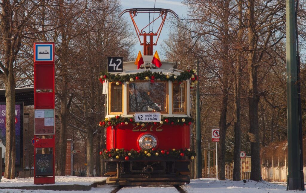 Tramway de Noël rouge et blanc décoré de guirlandes à Prague en hiver.