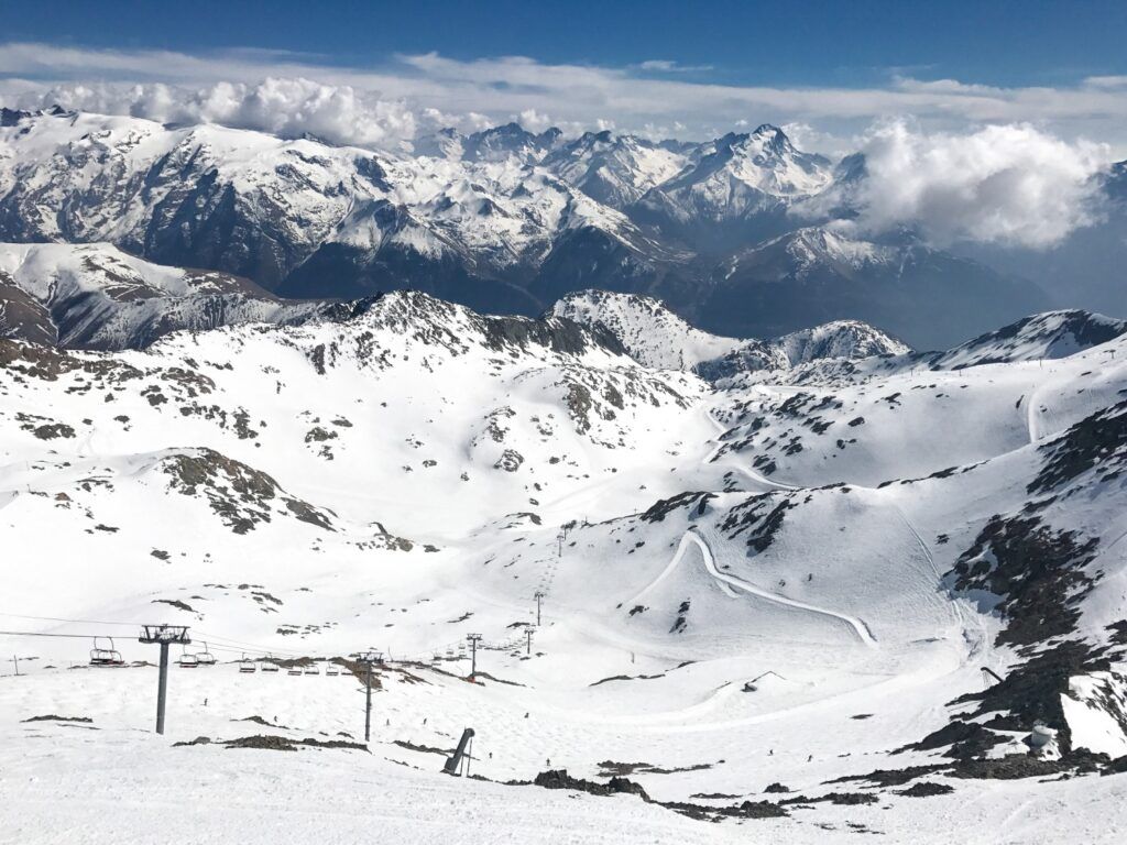 Panorama hivernal de l'Alpe d'Huez avec la piste de la Sarenne sous un ciel bleu dégagé.