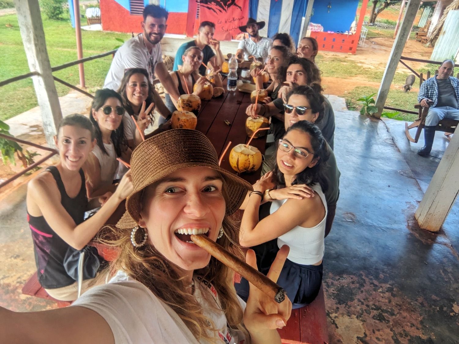 Un groupe de voyageurs WeRoad souriants profitant de noix de coco fraîches et de cigares à Cuba.