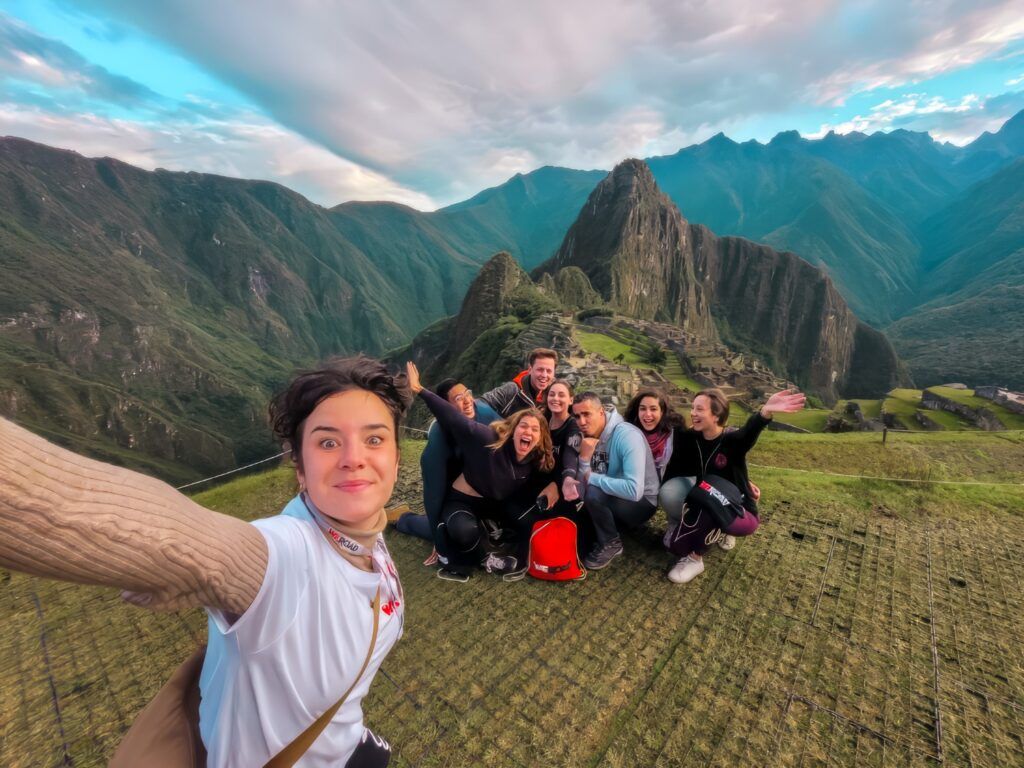 Un selfie d'un groupe de voyageurs WeRoad souriants devant les montagnes majestueuses de Machu Picchu au Pérou.