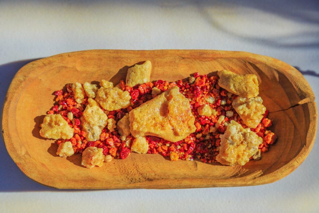 Un assortiment de fruits et de baies sauvages traditionnels du "bush tucker" australien présentés dans un bol en bois sculpté.