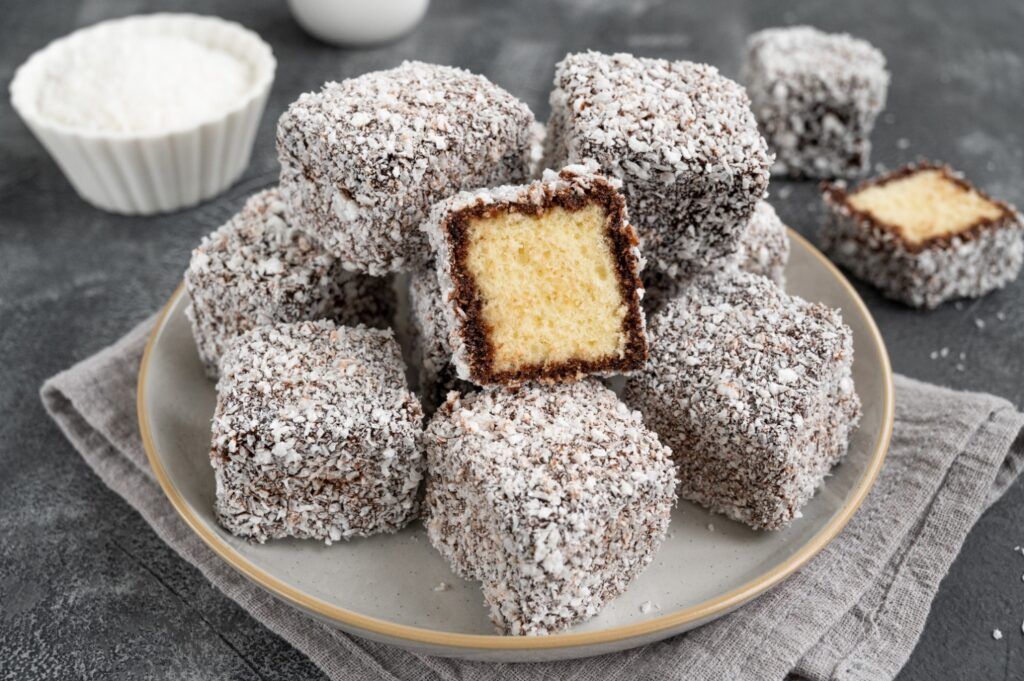 Une assiette de lamingtons australiens, des petits cubes de génoise enrobés de chocolat et de noix de coco râpée.