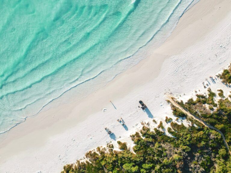 pPage de sable blanc et d'eaux turquoise cristallines bordée d'une végétation en Australie.