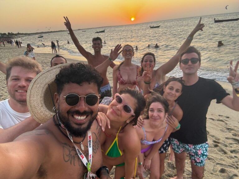 Un groupe de voyageurs WeRoad heureux prenant un selfie sur une plage brésilienne au coucher du soleil.