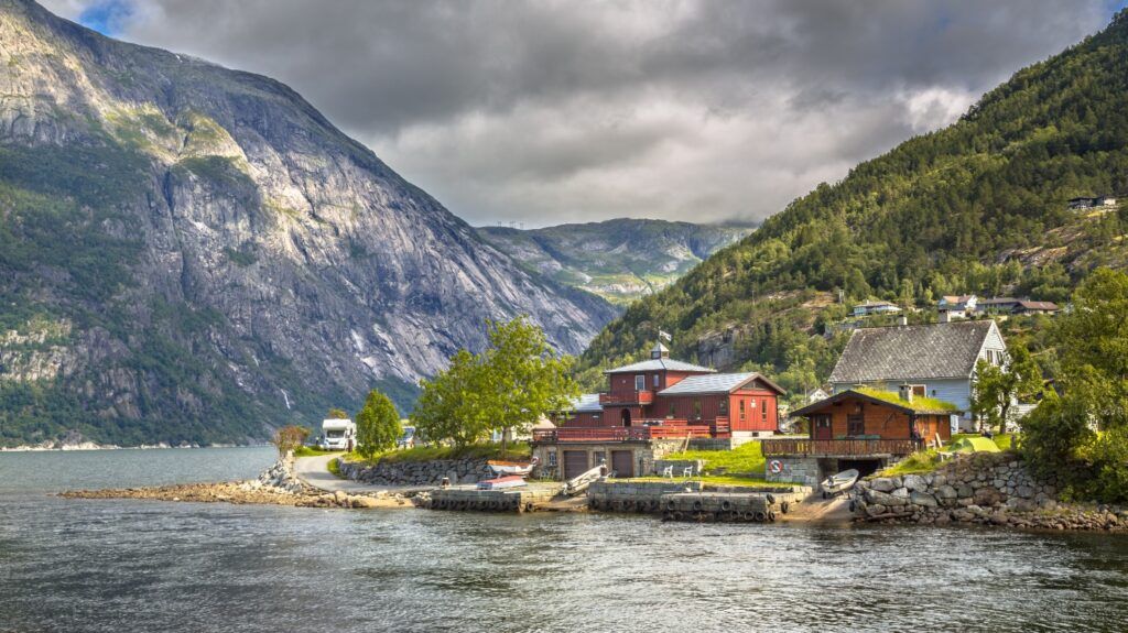 Le village d'Eidfjord sur les rives du Hardangerfjord, avec des maisons en bois traditionnelles au pied de montagnes escarpées en Norvège.