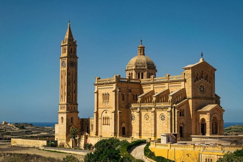 Basilique Ta' Pinu en pierre dorée avec clocher et coupole sous un ciel bleu, île de Gozo, Malte