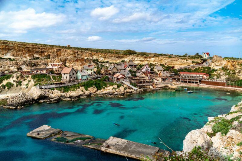 illage de Popeye aux maisons colorées surplombant la baie d'Ancre et son lagon turquoise à Malte