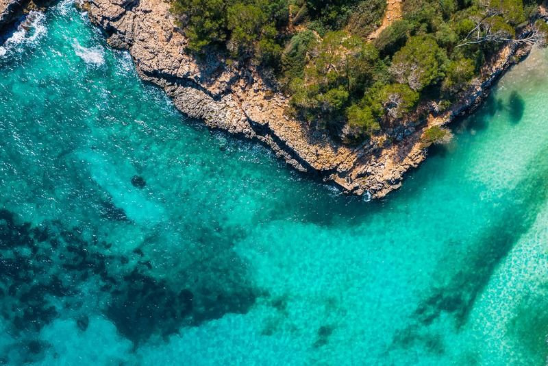 Vue aérienne par drone de la côte de Majorque avec mer turquoise cristalline, falaises rocheuses et pins méditerranéens