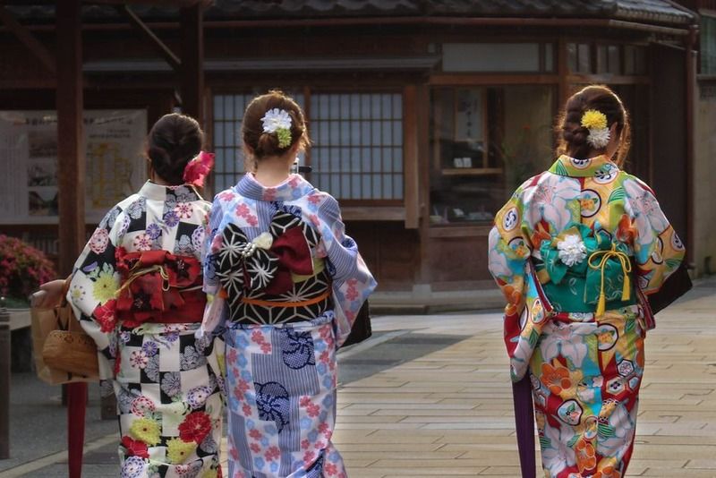 Trois femmes vêtues de kimonos traditionnels colorés se promenant dans une ruelle historique de Kyoto, Japon