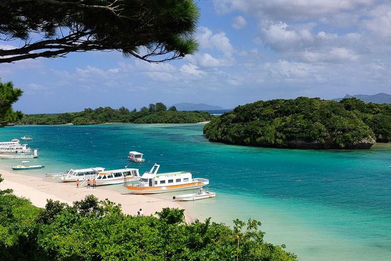 Lagon aux eaux turquoise avec des bateaux de croisière amarrés sur la plage de sable blanc d'Okinawa, Japon
